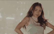 a woman in a pink and green dress is dancing with her hands on her hips