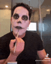 a man is applying makeup to his face with a brush and the hashtag tiktok at the bottom