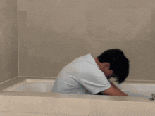 a man is sitting in a bathtub with a white shirt on