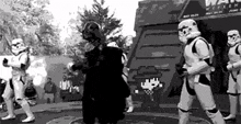 a group of stormtroopers are standing around a man in a black and white photo .