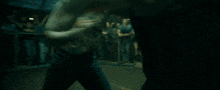 two men are fighting in a dark room and one of them has a tattoo on his arm