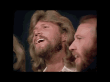 a man with a beard is smiling and looking up at the sky .