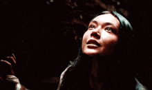 a close up of a woman 's face looking up in the dark .