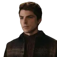 a man wearing a plaid jacket and a sweater looks at the camera