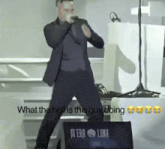 a man in a suit stands in front of a laptop that says " what the hell is this guy doing " on it
