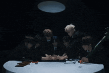 a group of men are gathered around a table with their hands on it