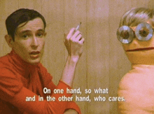 a man in a red shirt is talking to a puppet with the words " on one hand so what and in the other hand who cares "