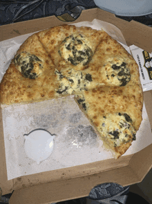 a pizza with a slice taken out of it is in a box with a packet of sauce next to it