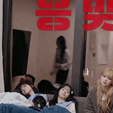 a group of girls are sleeping on a couch in front of a sign that says ' g5 '