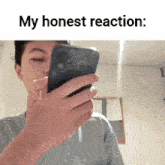 a young man is holding a cell phone in his hand and says my honest reaction .