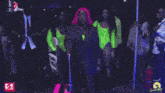 a woman in a pink wig is walking with a suitcase in a crowd