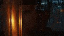 a man holding a gun in a dark room with a light behind him