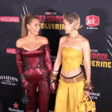 two women are standing on a red carpet with a jack in the box advertisement behind them