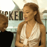 a woman in a white dress is talking to another woman in front of a sign that says locked