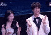 a man in a tuxedo stands next to a woman in a dress