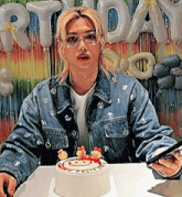 a woman in a denim jacket is sitting at a table with a cake