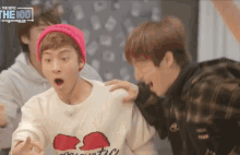 a man wearing a pink beanie and a sweater that says the 100 on it