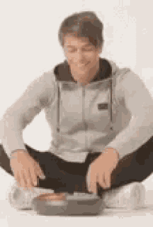 a man is sitting on the floor with his legs crossed playing a game .