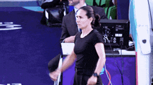 a woman in a black shirt is standing in front of a monitor that says ' s ' on it