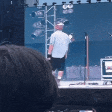 a man in a blue shirt is standing on a stage with a microphone