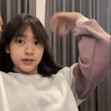 a young girl wearing a white shirt and a purple sweatshirt is making a funny face .