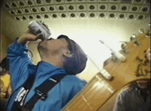 a man drinking from a can with the letter g on his belt