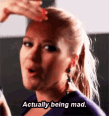 a woman is saying actually being mad while holding her hair