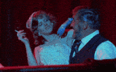 a woman in a white dress is smoking a cigarette next to a man