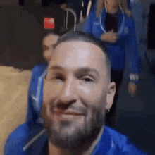 a man with a beard is smiling and looking at the camera while standing next to a woman .