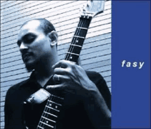 a man in a black shirt is playing a guitar in front of a blue background that says fasy