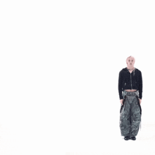 a woman in a crop top and cargo pants is dancing in front of a white background