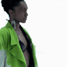 a woman wearing a green jacket and earrings