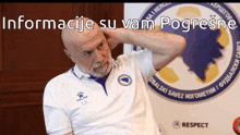 a man with a beard is sitting in front of a sign that says " informacije su vam pogresne "