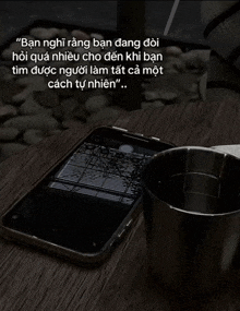 a phone is laying on a table next to a cup of water