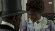 a man in a top hat looks at a woman in a purple dress with hbo written on the bottom