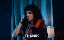 a man with long hair is talking on a red telephone with the words thanks written below him