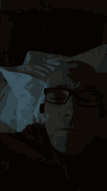 a man wearing glasses is laying on a bed