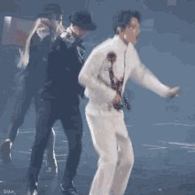 a man in a white suit is dancing on a stage with a woman in a black hat .