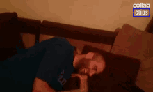 a man in a blue shirt is laying on a couch with a collab clip in the background