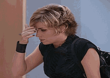 a woman wearing a black top is covering her face with her hand