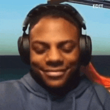 a man wearing headphones is smiling with his eyes closed and his mouth open .