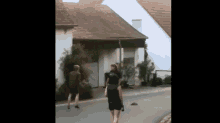 a group of people walking down a street in front of a house .