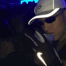 a man wearing a nike hat and sunglasses is standing in a crowd of people .