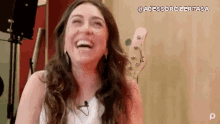 a woman is laughing while sitting in front of a guitar in a studio .