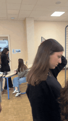 a girl in a black sweater is standing in a room