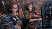 a man wearing headphones with the word blitzwolves on them is sitting in front of a computer