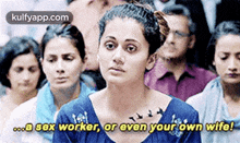 a woman in a blue shirt is sitting in front of a crowd of people .