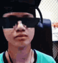 a person wearing sunglasses and a graduation cap looks at the camera