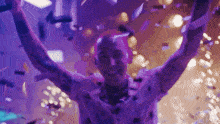 a man wearing headphones is dancing in a club with his arms in the air .