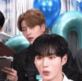 a group of young men are sitting in front of balloons .